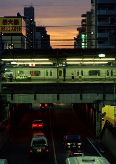 cars are driving down the road in front of an overpass at night with lights on