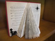 an open book sitting on top of a wooden shelf next to a christmas tree ornament