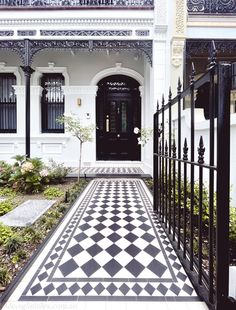 a black and white checkered floor in front of a house with an iron gate