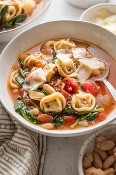 a white bowl filled with pasta and spinach soup