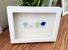 three blue and one green jellyfishs in a white frame on a wooden table