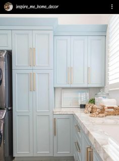 a kitchen with blue cabinets and marble counter tops, along with gold pulls on the doors