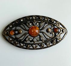 Beautiful interchangeable vintage italian made belt buckle. Plated in a antique brass. Cutout details, the shape reminds me of an eye. With large resin faux amber stone as a centre and rhinestones bordering. Designed to be worn with a 35mm belt strap.  Vintage Interchangeable Italian Made Belt Buckle filigreed Cutout Resin Faux Amber Gemstones and Rhinestones Unique Antique Brass Vintage Belts With Rectangular Antique Buckle, Antique Bronze Belt Buckle, Vintage Brown Jewelry With Antique Buckle, Brown Antique Buckle Belt Buckles For Festival, Vintage Antique Buckle Belt In Distressed Brown, Vintage Belts With Antique Buckle, Adjustable, Amber Gemstone, Amber Stone, Unique Antiques