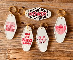 four key chains with different designs on them sitting on a wooden table next to each other