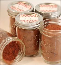 four jars filled with different types of brown stuff on top of a white countertop