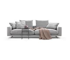 a gray couch with pillows and a blanket on it's back end, in front of a white background