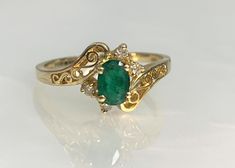 Dainty Emerald Ring, Emerald Ring Vintage, Filigree Gold Ring, Emerald Bypass Ring, Oval Emerald Ring, Dainty Gold Ring, Vintage Bypass Ring A delicate and delightful vintage bypass ring featuring an oval shaped emerald center stone weighing 0.46 carats accented by 0.05 carats of white diamonds set in solid 14k gold with unique filigree detailing. *Ring size: US 7 1/2 *Complimentary resizing is available up to 3 sizes larger or smaller than stated size. *Ring weight: 2.26 grams Stone dimensions: Oval Emerald Ring With Intricate Design For Wedding, Oval Emerald Ring With Intricate Design, Fine Jewelry Ring With Intricate Oval Design, Oval Ring With Intricate Design In Fine Jewelry, Oval Fine Jewelry Ring With Intricate Design, Vintage Engagement Rings Unique 1920s Emerald, Signate Ring, Soul Bond, Oval Emerald Ring