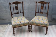 two wooden chairs sitting on top of a striped rug