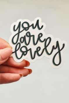 someone holding up a sticker with the words you are lovely in black and white