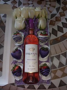 a bottle of wine sitting on top of a table next to chocolate covered strawberries