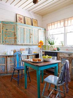 an old fashioned kitchen with blue chairs and wooden table