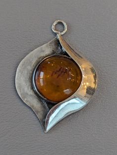 "Sterling Silver signed Modernist Amber pendant. Pendant has large Amber cabochon bezel set in solid Sterling Silver.nPendant is fully hallmarked and will arrive gift boxed. * HALLMARKS 925, and a couple of makers marks which I couldn't identify. * MEASUREMENTS 1 3/4\" x 1 1/4\". * WEIGHT  6 Grams. * CONDITION In very good to excellent condition. * MATERIALS Sterling Silver, Amber." Mid Century Pendant, 925 Jewelry, Bezel Setting, Makers Mark, Amber, Sterling Silver Pendants, Silver Pendant, Jewelry Gifts, Gifts For Women