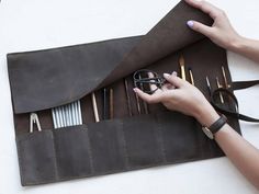 a woman is holding scissors in her leather case