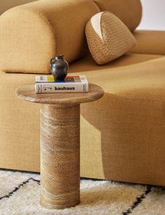 a table with a vase sitting on top of it in front of a couch and ottoman