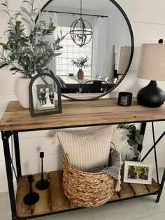 a wooden table topped with a mirror next to a vase filled with flowers and plants