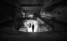 a person walking up some stairs with graffiti on the wall behind them and an exit way leading to another room