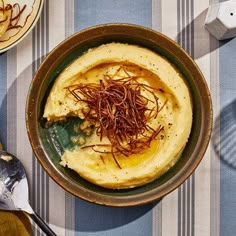 a bowl filled with food sitting on top of a table next to utensils