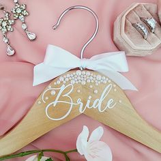 a wooden hanger with the word bride written on it next to jewelry and flowers