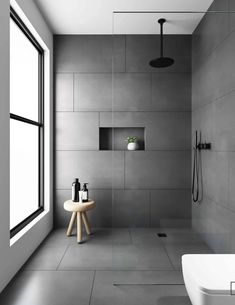 a modern bathroom with white walls and grey flooring, along with a large window