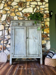 an old wooden cabinet sitting on top of a hard wood floor next to a stone wall