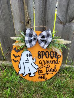 a wooden sign that says spook around and find out with a ghost on it