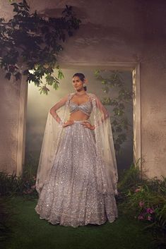 Featuring a metallic grey tulle lehenga embroidered fully by hand with various ornamental lustre sequences and Japanese rainbow bugle beads. It is paired with a scallop dupatta and stylised blouse .From Aneesh Agarwaal's Ellora collection.DELIVERY TIMEPlease allow 8-12 weeks for your outfit to arrive.FABRIC DETAILSNetProfessional cleaning only. Silver Festive Dress With Sheer Dupatta, Festive Silver Dresses With Sheer Dupatta, Designer Silver Organza Lehenga, Designer Silver Choli With Sheer Dupatta, Silver Embellished Organza Lehenga, Embellished Silver Organza Lehenga, Designer Silver Lehenga With Sheer Dupatta, Designer Embellished Silver Lehenga, Silver Anarkali Style Hand Embellished Sharara