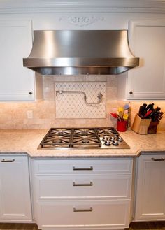 a stove top oven sitting inside of a kitchen next to white cabinets and counter tops