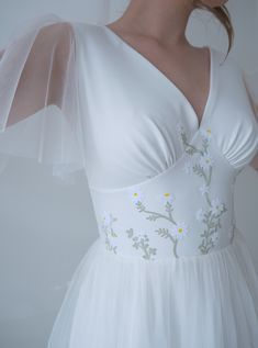 a woman wearing a white dress with flowers on it