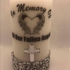 a white candle with an angel cross on it and the words memory of our fallen angels