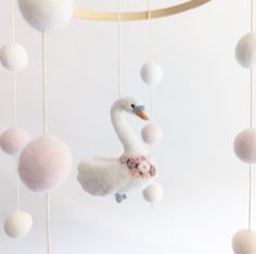 a white swan mobile with pink and white balls hanging from it's sides in front of a white background