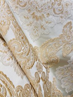 gold and white brocaded fabric with intricate designs on it's edges, closeup