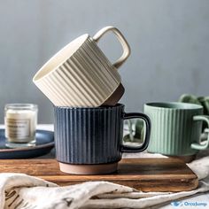 three coffee cups stacked on top of each other in front of a plate and napkin