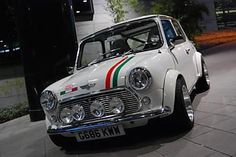 an old white car with red, green and white stripes parked on the side of the road