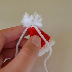 a hand is holding a small red and white crocheted ornament in it's palm