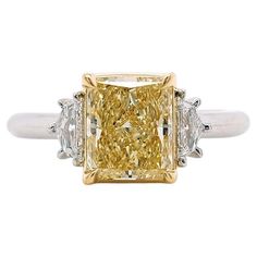 a fancy yellow diamond ring with three diamonds on the band and two white gold shoulders