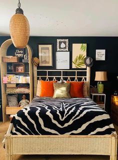 a bedroom with zebra print bedding and orange pillows on the headboard, in front of a bookshelf