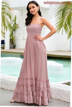 a woman standing in front of a pool wearing a long dress with tiered ruffles