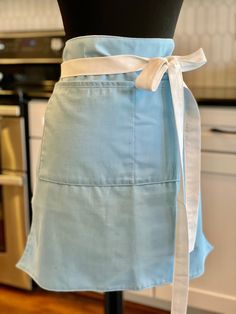 a woman's blue apron with a white ribbon tied around the waist