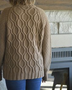 a woman standing in front of a fireplace wearing a sweater