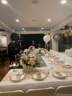 two men standing at the end of a long table with plates and silverware on it