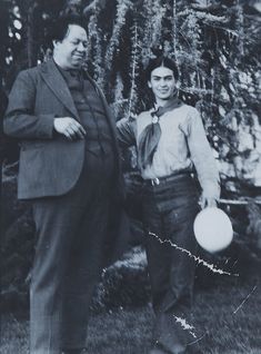 an old black and white photo of two people holding frisbees