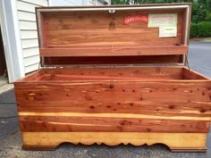 an old fashioned wooden chest sitting on the side of a road in front of a house