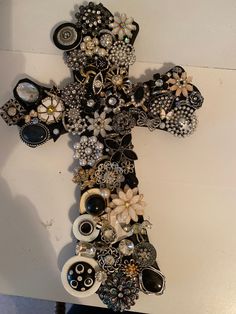 a cross made out of beads and other items is hanging on the side of a wall