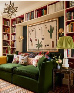 a living room filled with green couches and lots of books on the shelves behind them