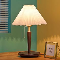 a lamp sitting on top of a wooden table next to a framed photograph and a small mirror