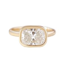 a gold ring with a cushion cut diamond in the center and a thin band around it