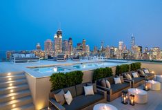 an outdoor seating area on the roof of a building with city lights in the background