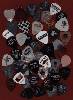 many different types of guitar picks on a red surface