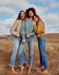 three women are standing in the middle of a field