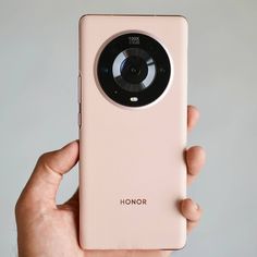 a person holding up a pink phone with a camera on it's front and side